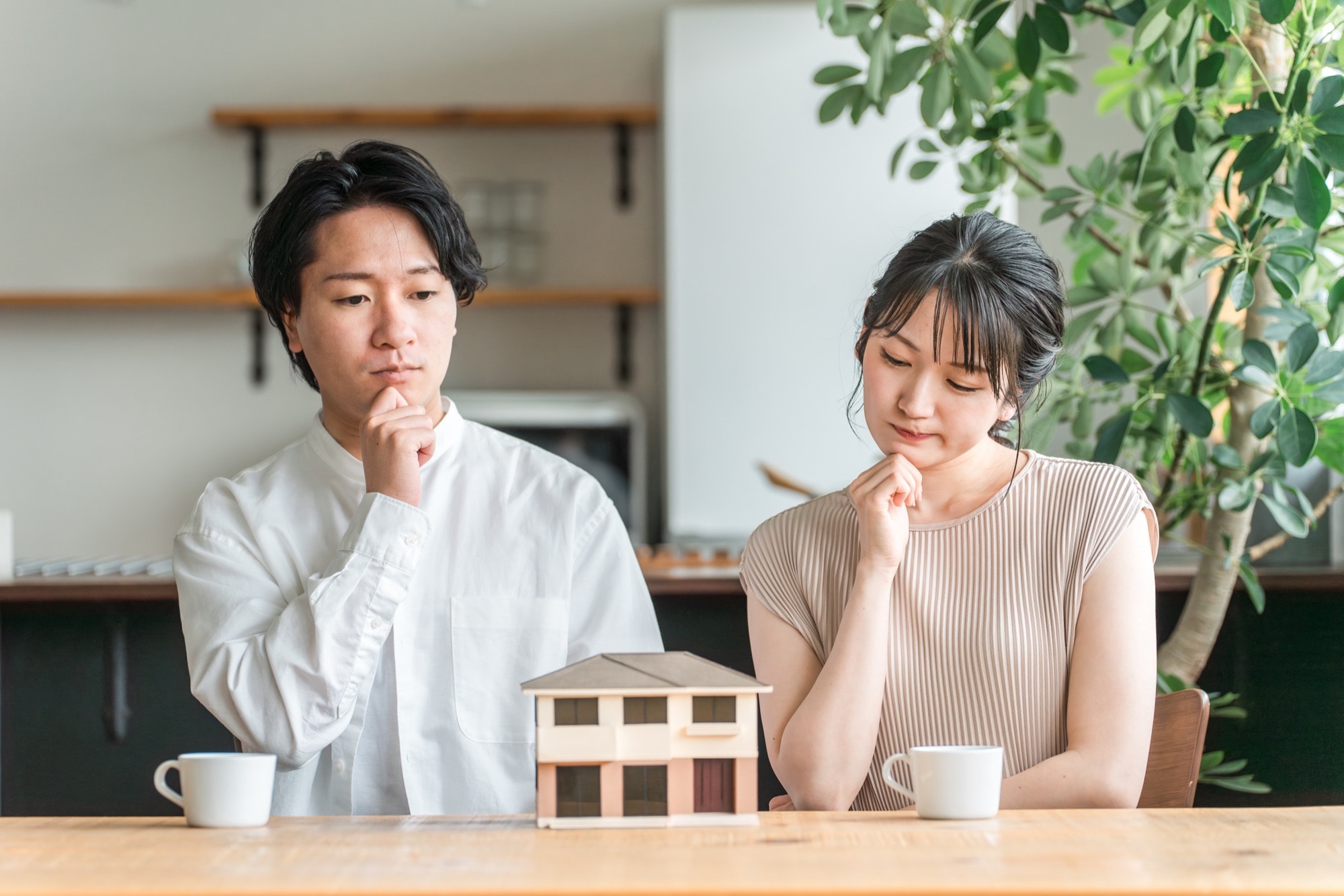 住宅模型を見てマイホームの間取りを検討する若い夫婦