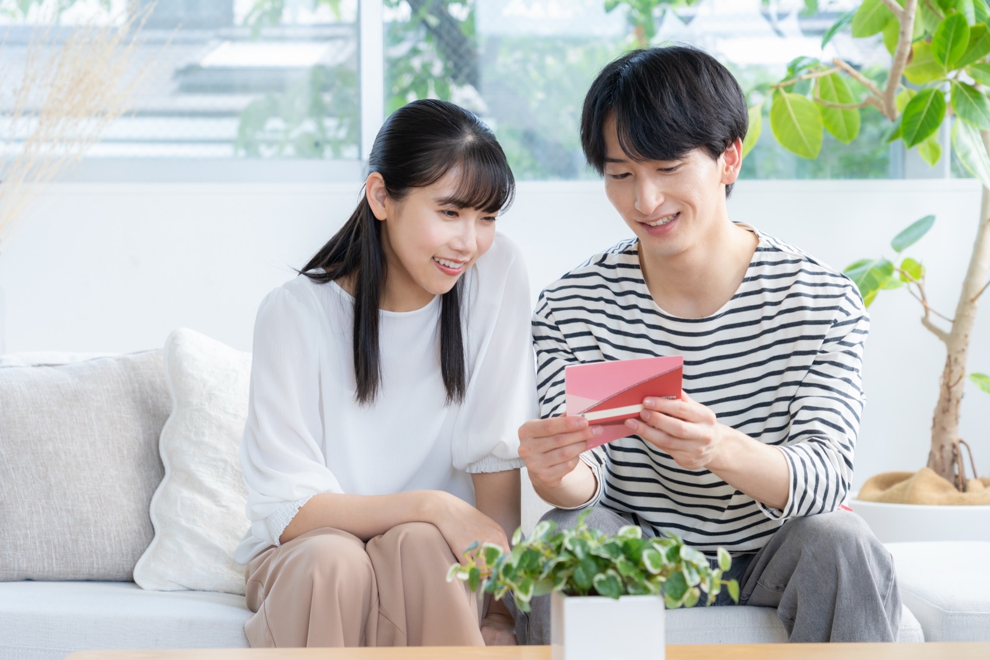 リビングで通帳を見る若い夫婦