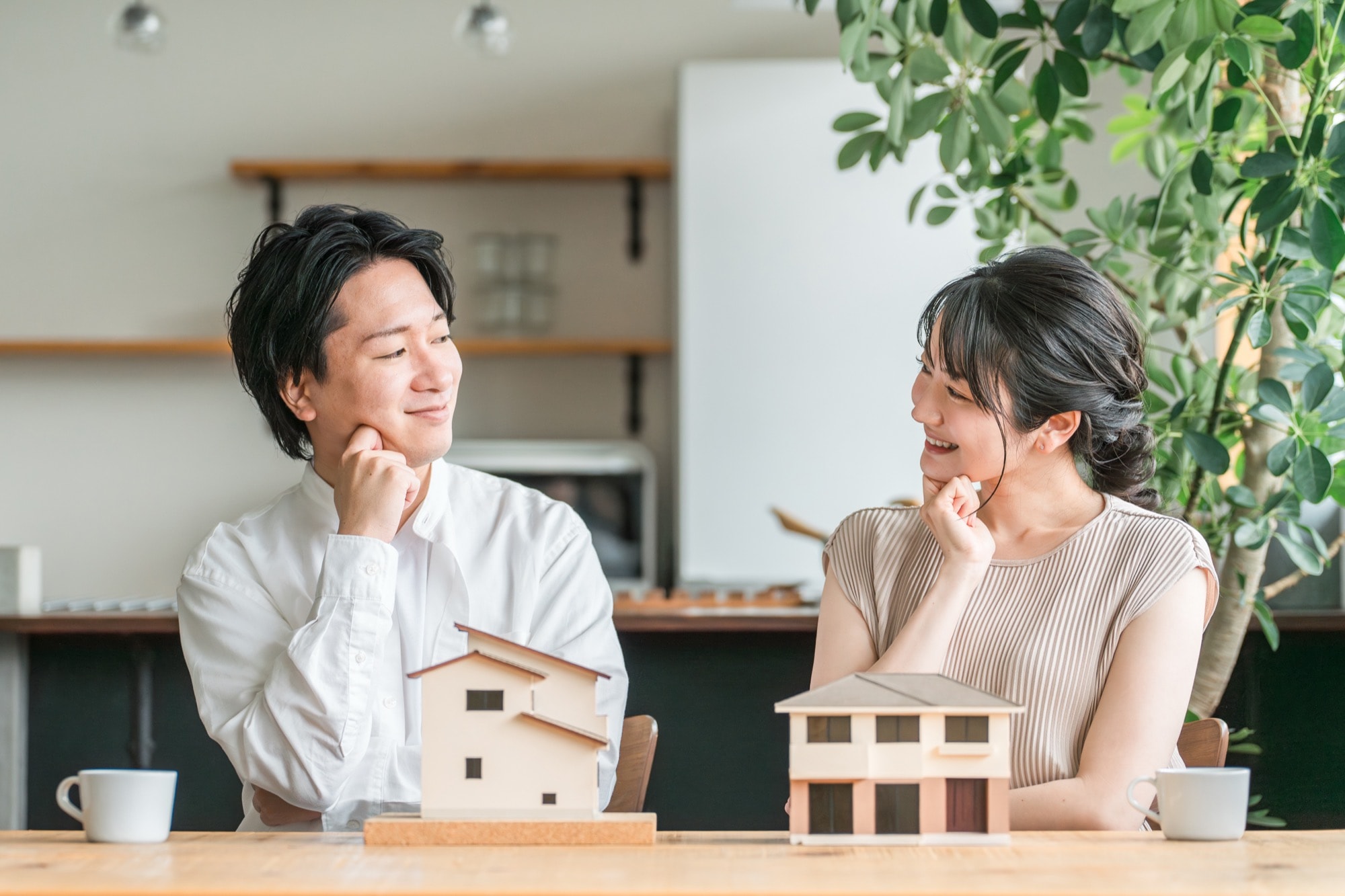 住宅模型を見てマイホームの間取りを検討する若い夫婦